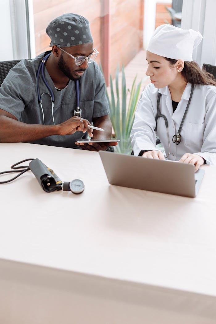 Crafting Captivating Headlines: Your awesome post title goes here Two doctors discussing patient care with devices on a glass table indoors.