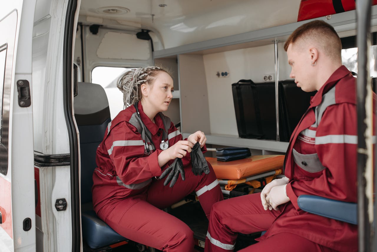 Services Two paramedics in uniform preparing equipment inside an ambulance.