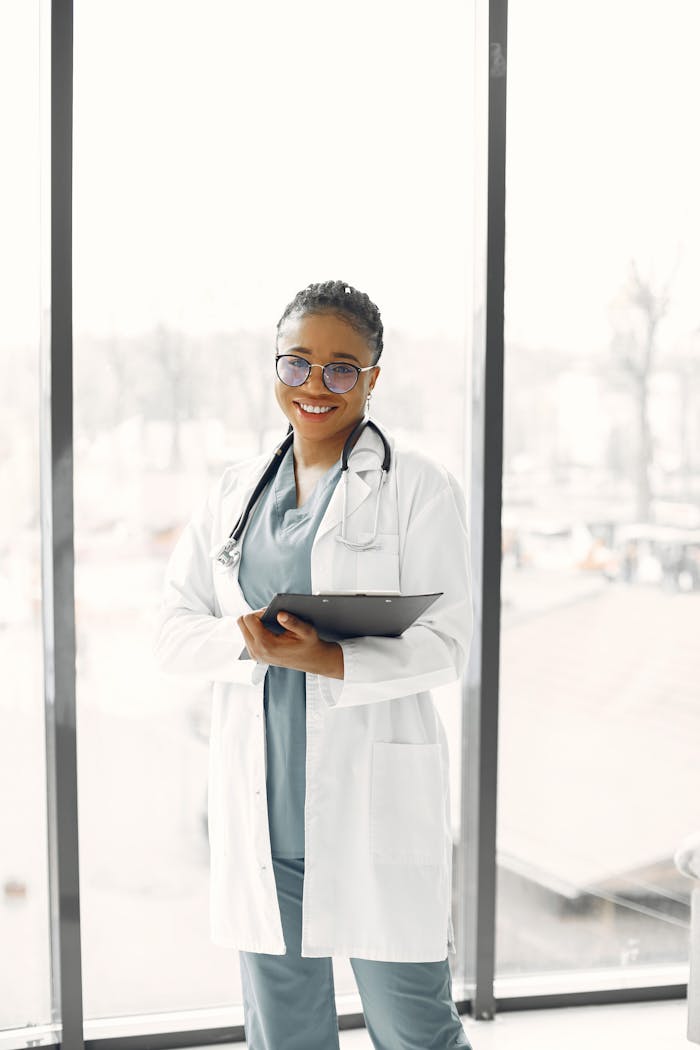 Home Smiling female healthcare professional with clipboard and stethoscope indoors.